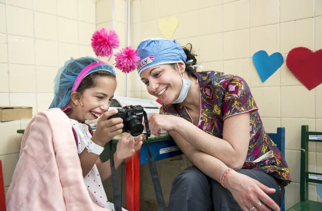 Niña junto a cirujano de Operación Sonrisa mirando su foto en una cámara